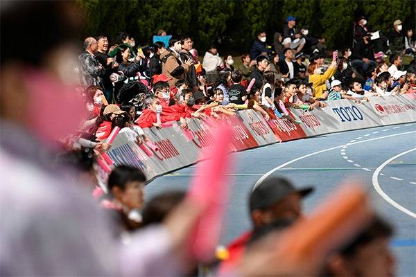 トラックの真横でブリキ看板を叩き応援する観客