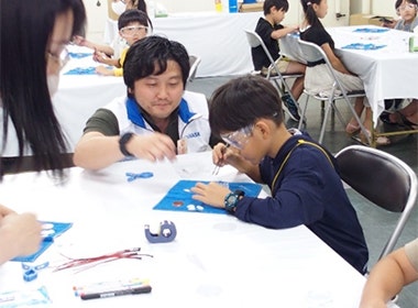 真剣な表情で、銅板、塩水で濡らした不織布、アルミ板を順番に重ねて、電池をつくっていく