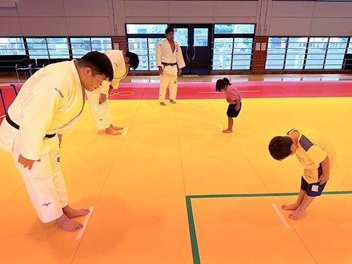 Children learning judo etiquette from the athletes